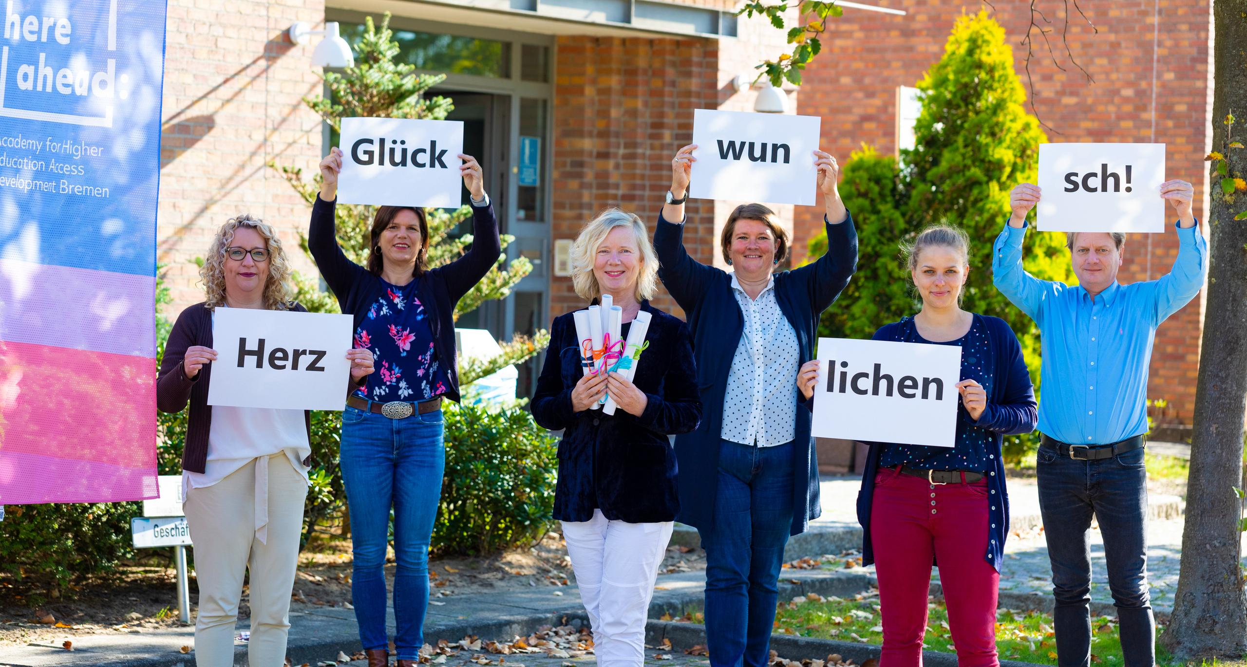 Menschen mit "Herzlichen Glückwunsch"-Schildern